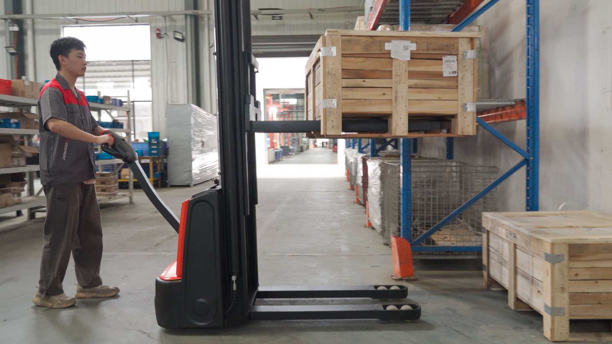 Thumbnail of Operator using EP Equipment ESA121-D electric walkie stacker to lift and move wooden crates safely in narrow warehouse aisles.