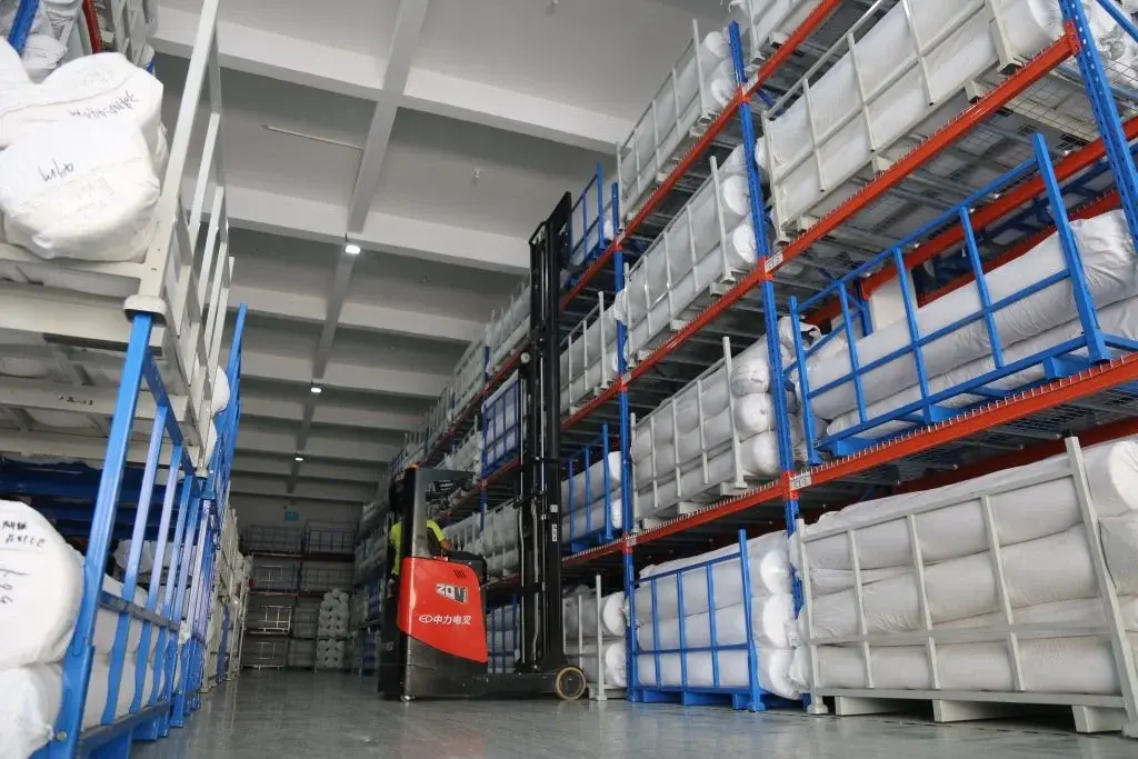 EP Equipment CQD15S 1.5T electric narrow aisle reach truck working in textile warehouse, stacking rolls and goods with precision.