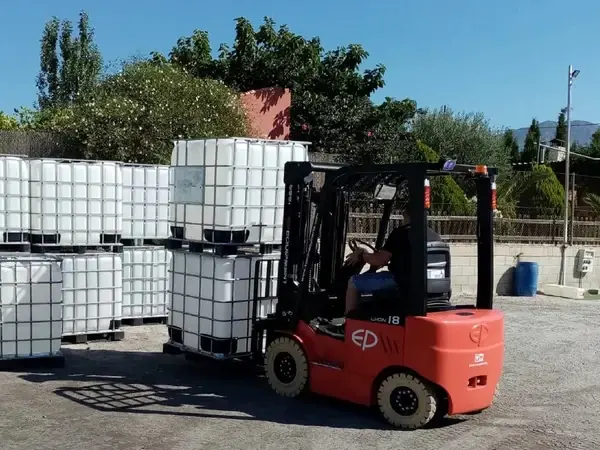 EFL181 lithium electric forklift moving IBC water tanks outdoors at an industrial site