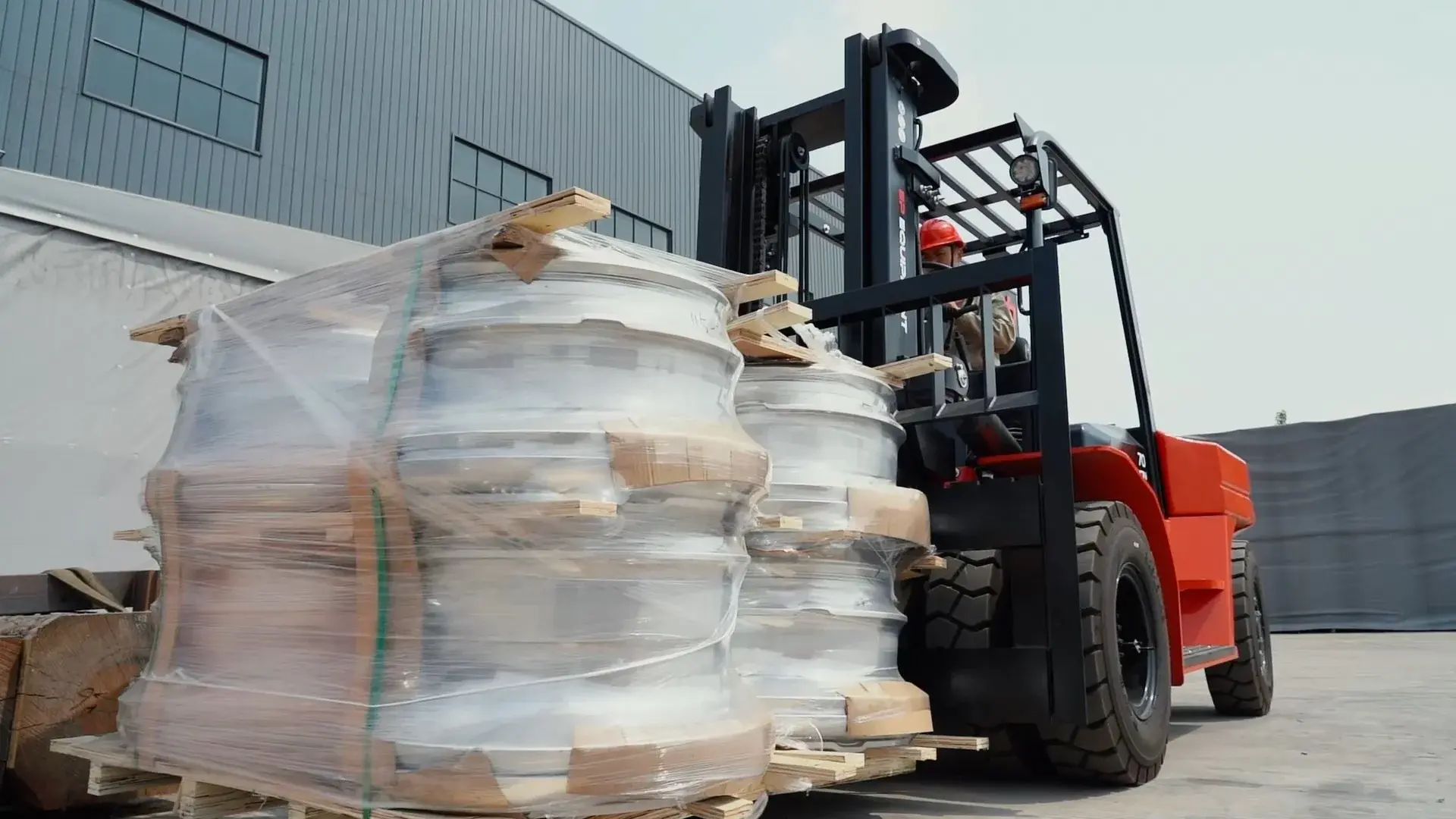 EP EFL703 electric forklift transporting heavy industrial rolls outside a warehouse.