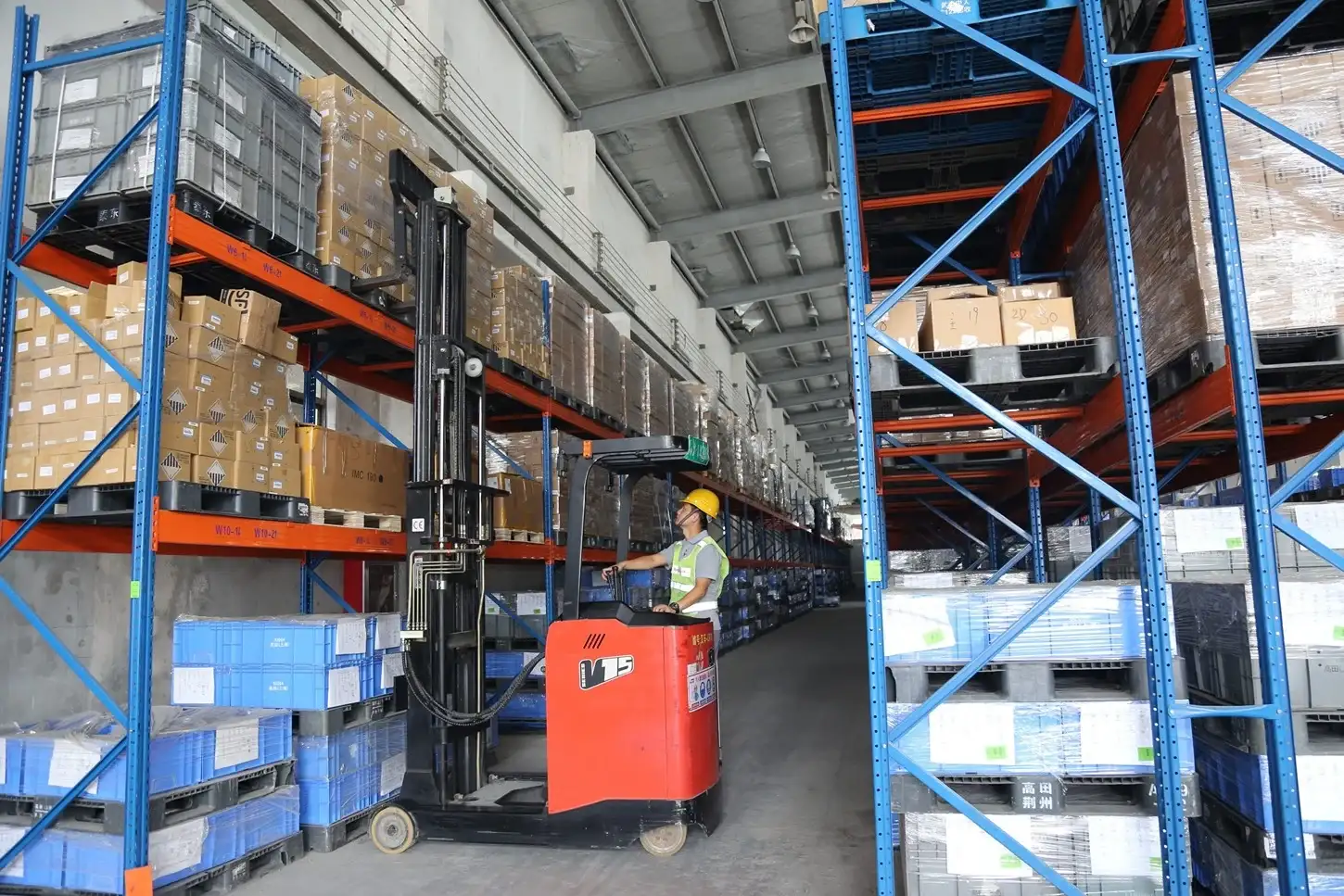 Operator driving EP Equipment CQD15S 1.5T electric narrow aisle reach truck to lift and stack goods on high warehouse racks with precision.