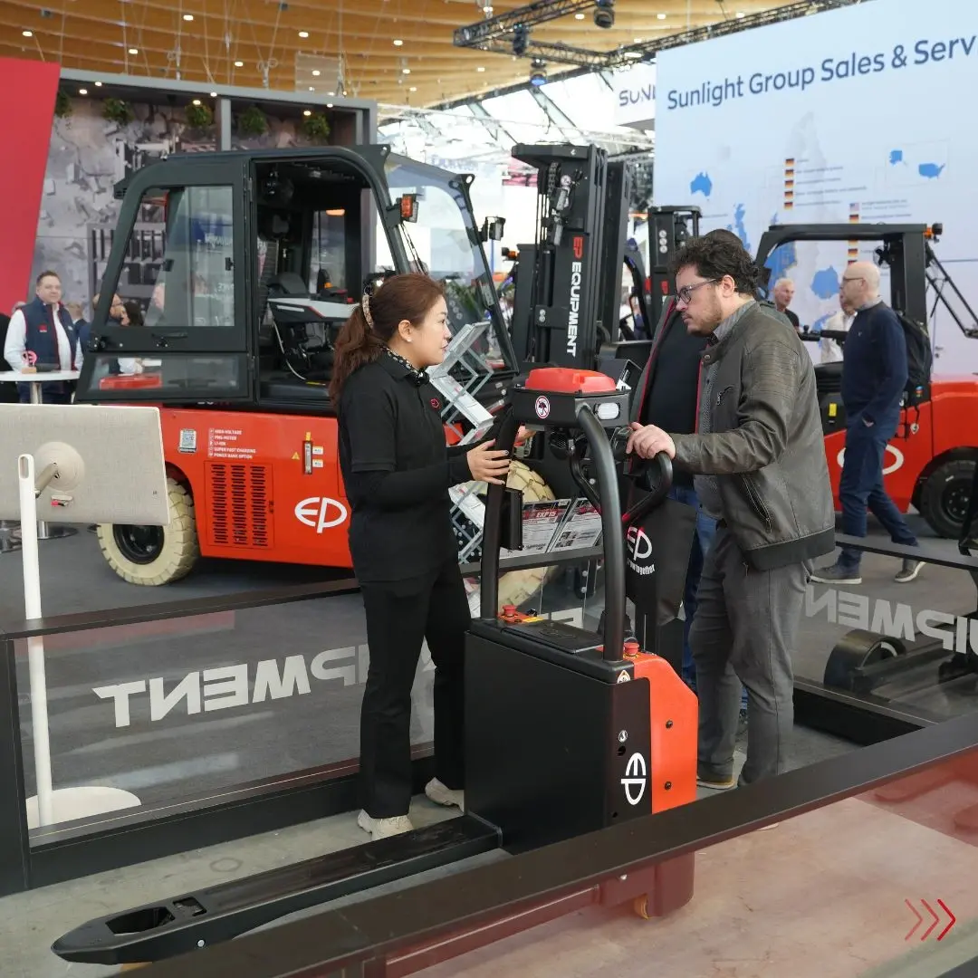 EP Equipment staff demonstrating an electric pallet truck to a visitor during the trade fair.