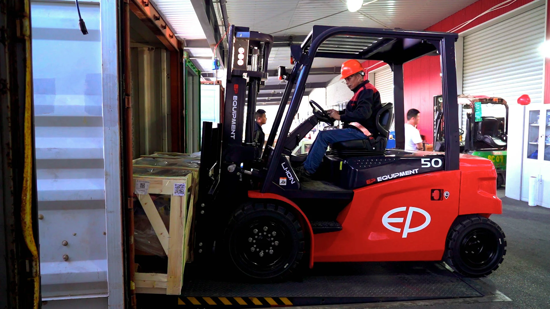 Operator loading cargo into a container using EP Equipment CPD50L1 four-wheel lithium-ion electric forklift, showcasing high efficiency in logistics applications.