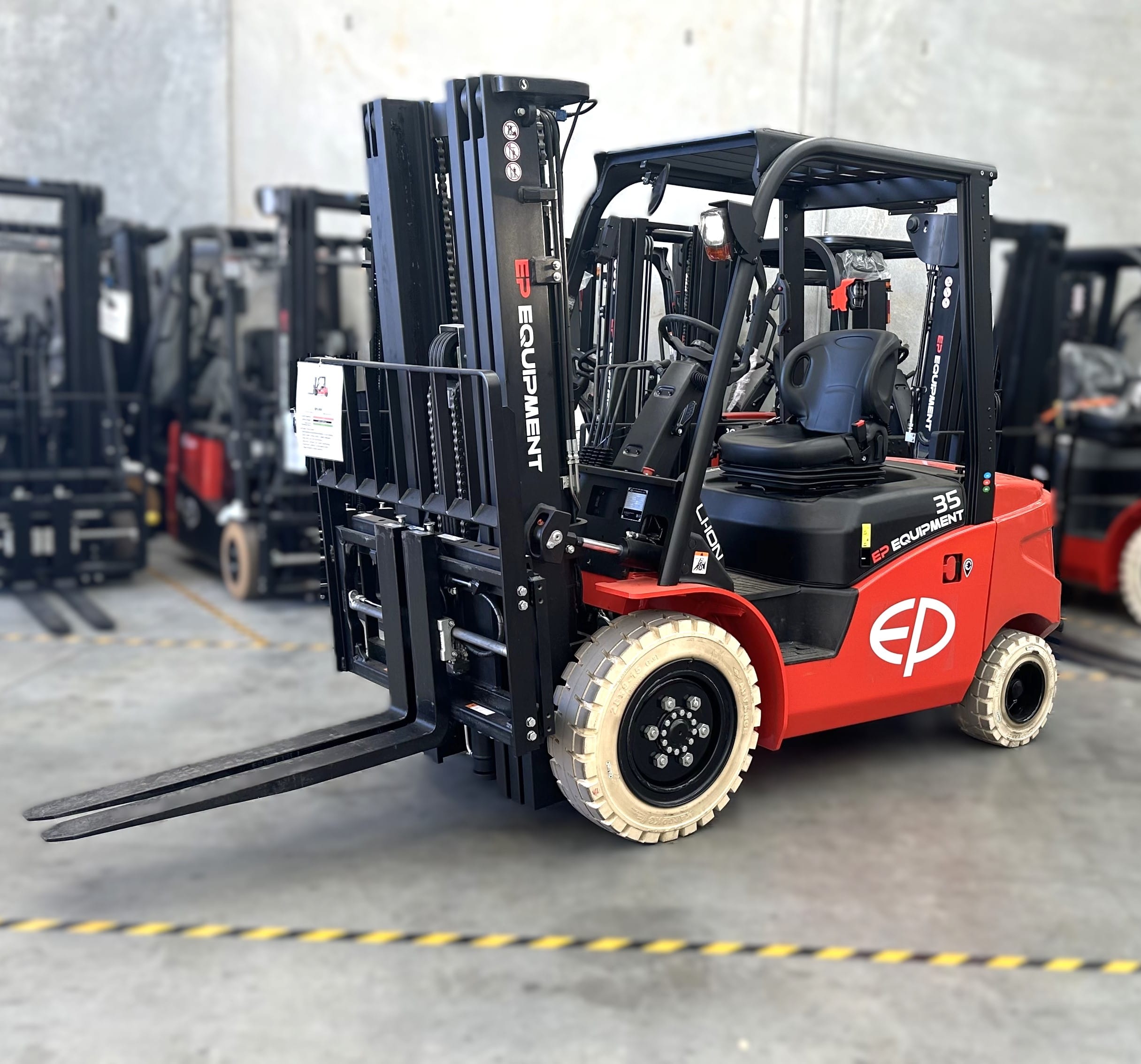 Front view of EFL353 four-wheel lithium counterbalance forklift by EP Equipment stored in warehouse with other forklifts