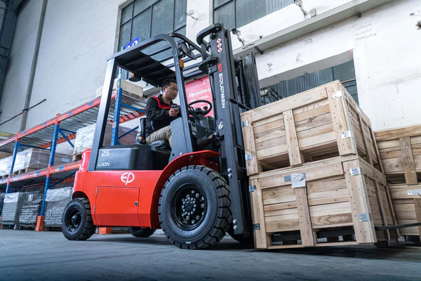 Operator using EP Equipment EFX252 lithium-ion electric forklift to handle wooden crates in a warehouse, demonstrating powerful lifting and precise control for medium-duty applications.