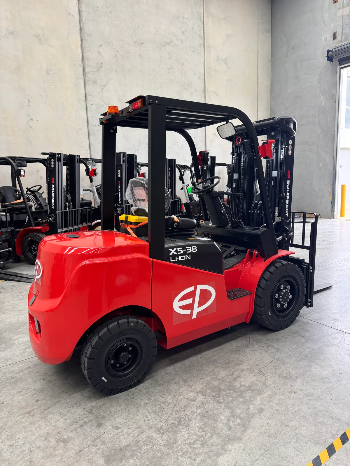 EP Equipment EFX5-381 3.8T lithium-ion electric forklift in the EPower Forklift warehouse alongside other EP trucks, rear-right view