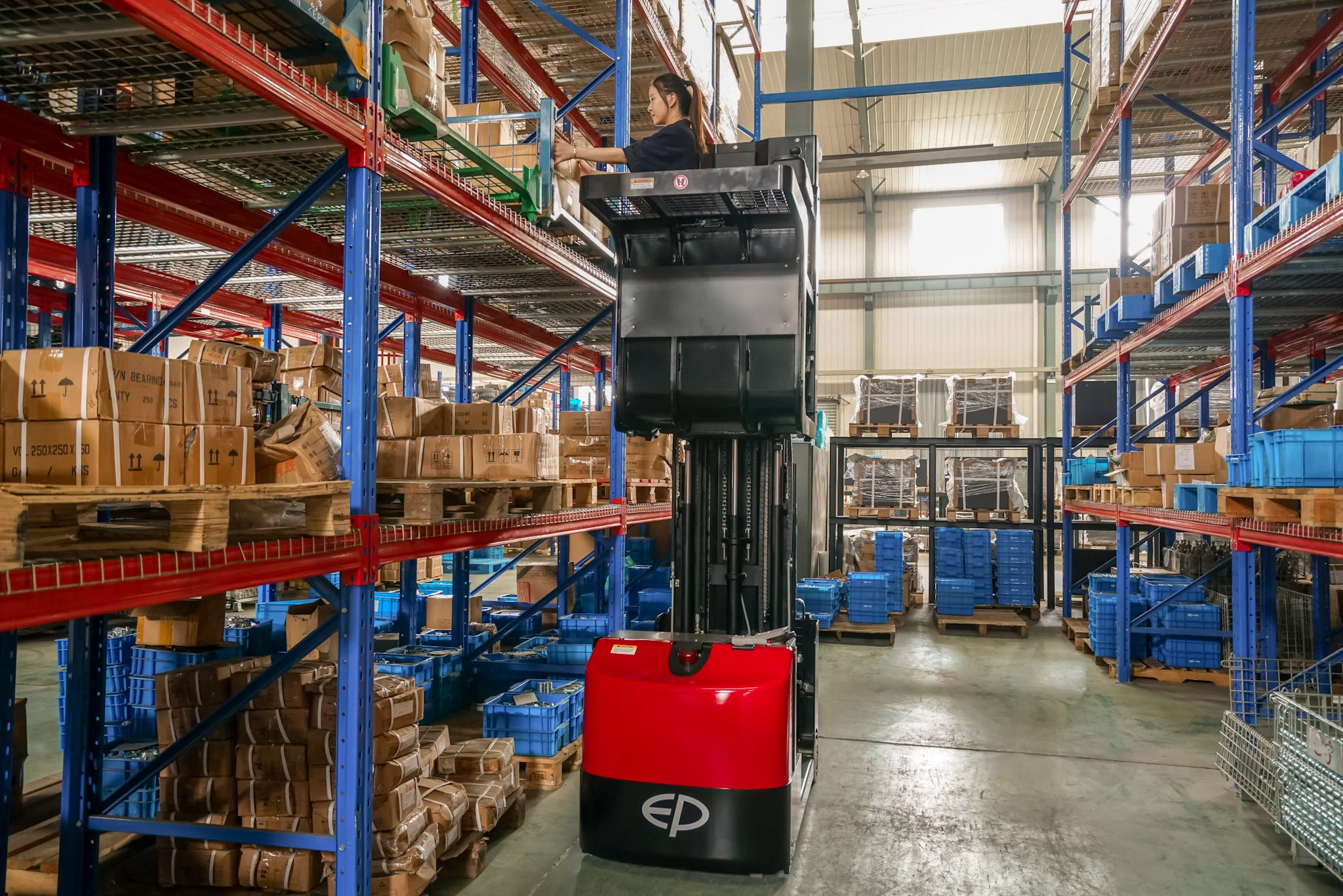 EP Equipment JX1 electric order picker lifting operator for high-level picking in warehouse aisles.
