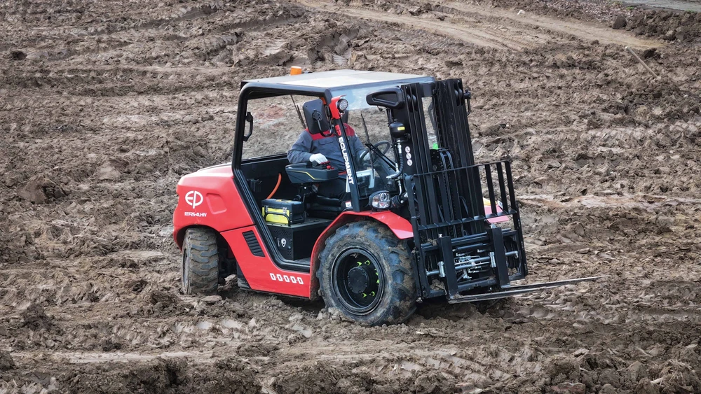 EP Equipment RTF25-4L1-HV electric rough terrain forklift driving through deep mud, showcasing strong off-road performance.